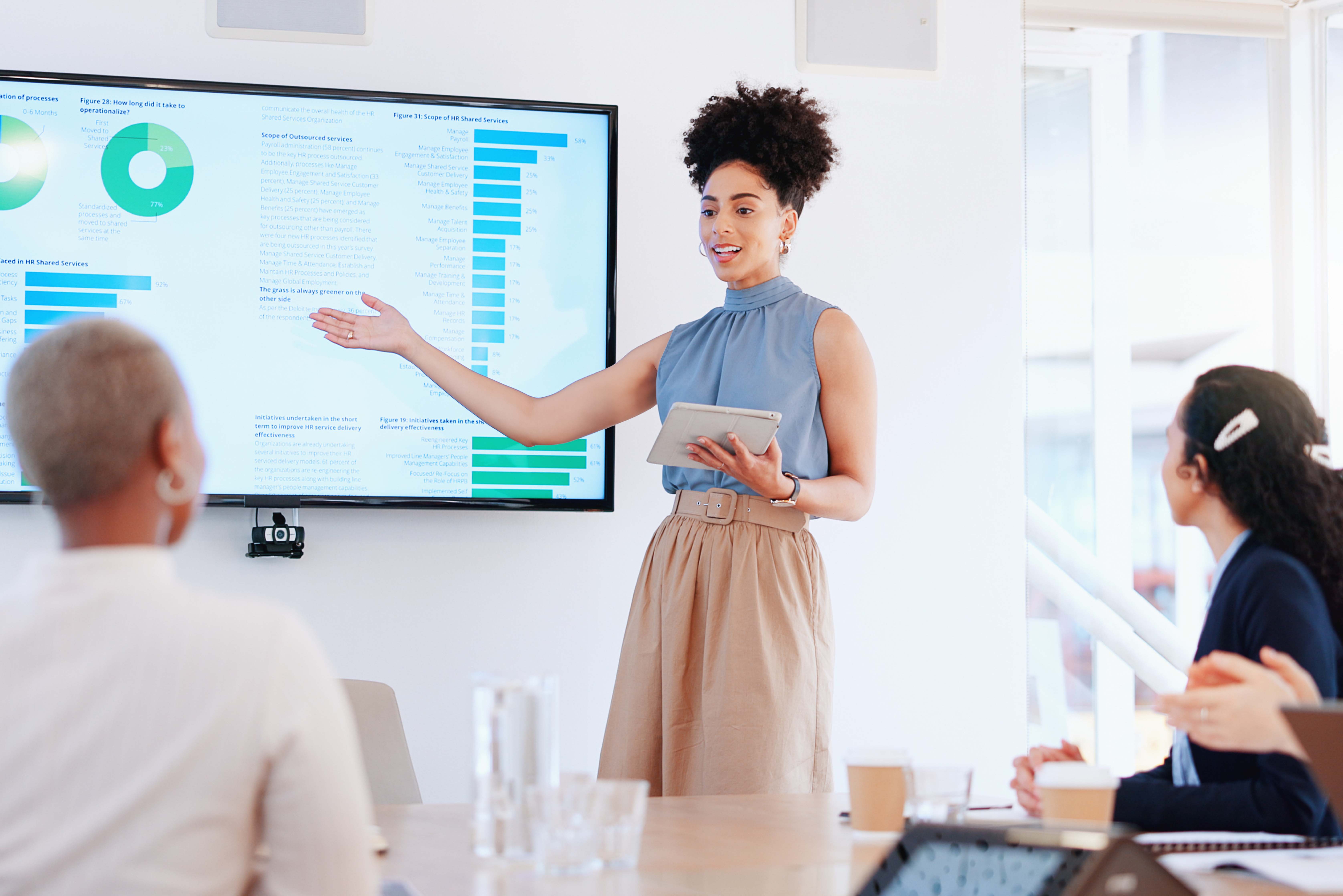 Young business professional giving a presentation in front of a digital screen presenting to multiple people